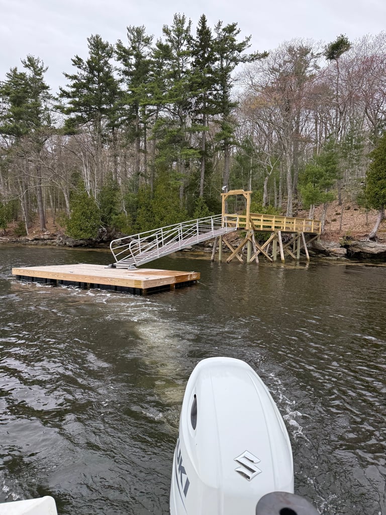 White jet ski in foreground with wooden dock and bridge over river surrounded by bare and evergreen trees