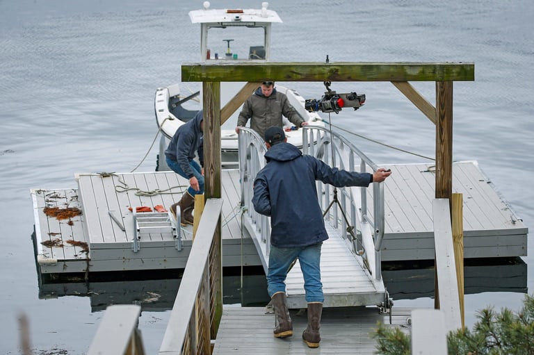 People boarding a white boat at a wooden dock with water visible in the background